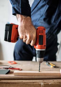 A carpenter using a drill on a wood