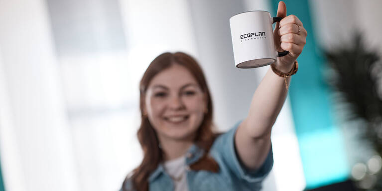 happy employee at ECOPLAN presenting a coffee cup